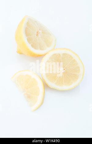 Cut lemon and lemon wedge arranged on a white background. Stock Photo