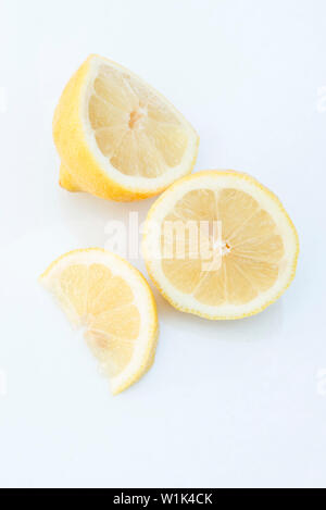 Cut lemon and lemon wedge arranged on a white background. Stock Photo