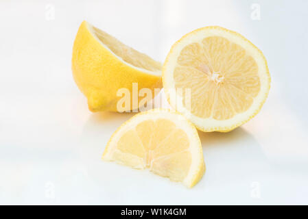 Cut lemon and lemon wedge arranged on a white background. Stock Photo