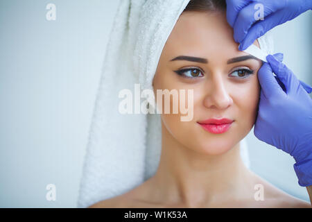 Skin care. Experienced cosmetician pulling out brows Stock Photo