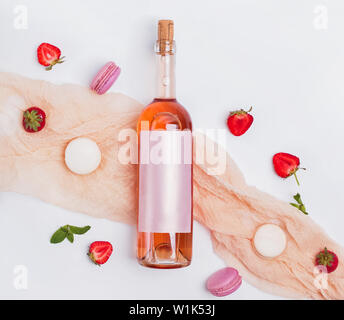Rose wine, strawberries and french dessert macarons on the white background, top view. Creative summer composition Stock Photo