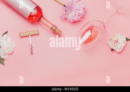 Rose wine and beautiful peonies on the pink background. Creative summer composition. Stock Photo