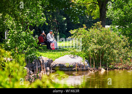 Montreal, Canada - June, 2018: Senior Asian couple sitting on the bench and eating their sandwiches at lachine rapids park in Montreal, Quebec, Canada Stock Photo