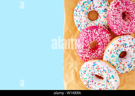 Colorful donuts on paper with blue copy space background Close up, top view. Stock Photo