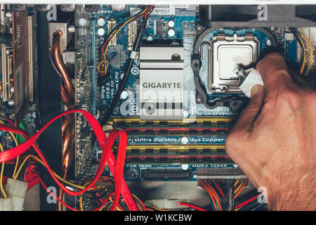 Maykop, Russia - September 17, 2016: male hand applies thermal grease on intel processor top view close-up Stock Photo