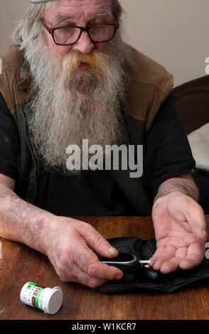 Elderly man with type 2 diabeties conducting a blood glucose test Stock Photo