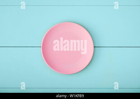 Pink empty plate on turquoise wooden table. Top down view with copy space. Stock Photo