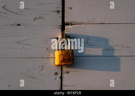 rusty lock hanging on a wooden door at sunset Stock Photo