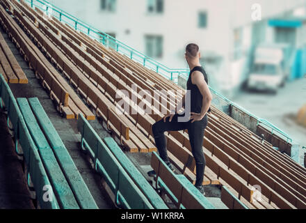 Caucasian man trains in running on the stairs. Track and field runner in sport uniform training outdoor. athlete, top view. step exercises. Stock Photo