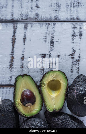 halved avocados on white wooden table Stock Photo - Alamy