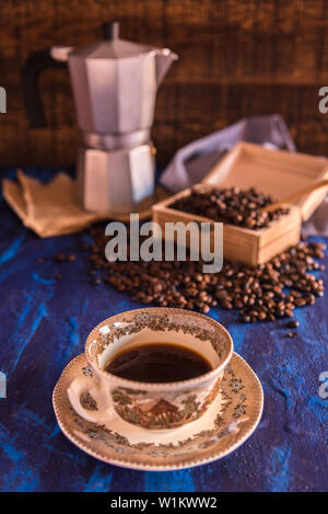 Freshly made coffee served in a cup and coffee beans in a wooden box on a blue background Stock Photo