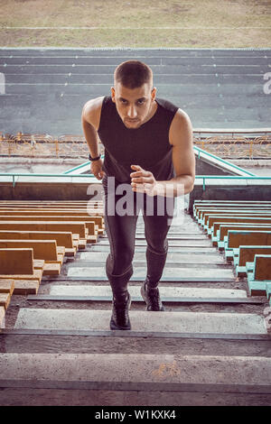 Caucasian man trains in running on the stairs. Track and field runner in sport uniform training outdoor. athlete, top view. step exercises. vertical. Stock Photo