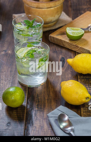 Mojito cocktail on a wooden table with its peppermint,lemon and lime ingredients Stock Photo