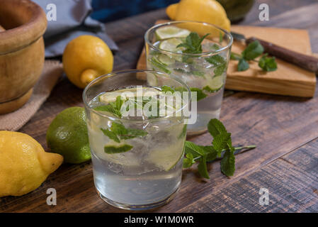 Mojito cocktail with its on ingredients peppermint,lime and lemon on a wooden table Stock Photo