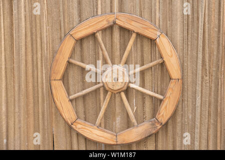 description: Fragment of an ancient wall with a blue door, an old wooden wheel and a drainpipe Stock Photo