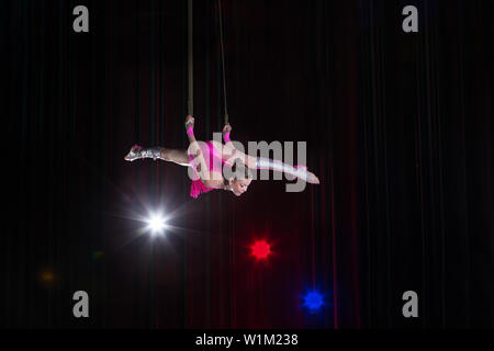 Circus artist acrobat performance. The girl performs acrobatic elements in the air. Circus gymnast on the stage Stock Photo