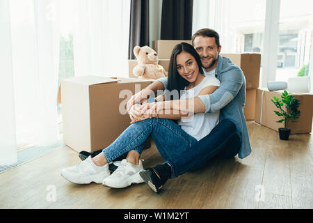 Man hug his young wife, the sitting at new house. Moving new apartment, young couple rental house Stock Photo