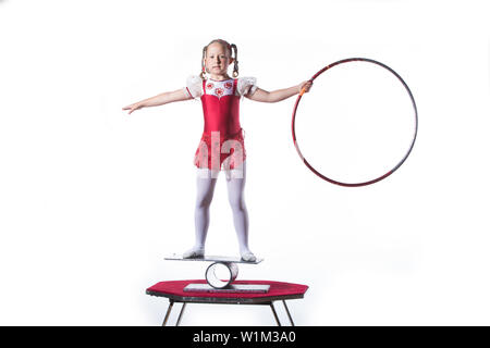Little girl balancing act on white background. Young gymnast balancing actress with the hoop Stock Photo