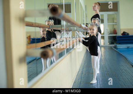 Little girls at the ballet machine. Lesson choreography. Young ballerinas.. Training of the initial group on gymnastics.Acrobatics lesson Stock Photo