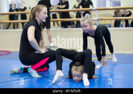 . Indicative training circus school.The coach trains children. Female athlete teaches girl gymnastics or circus art Stock Photo