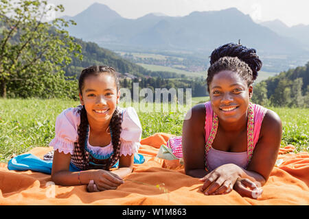 Teenage girls lying on picnic blanket, Bavaria, Germany Stock Photo
