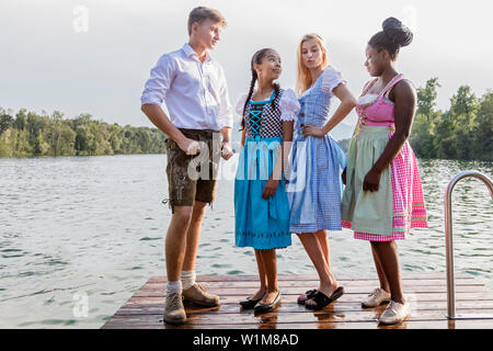 Teenage friends standing on pier, Bavaria, Germany Stock Photo