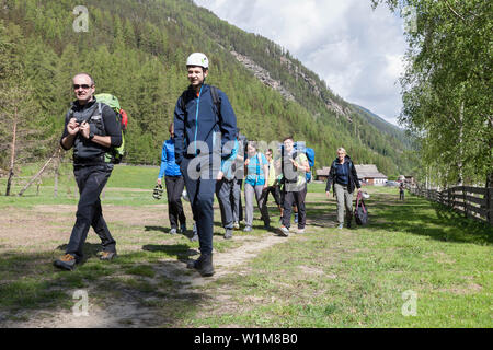 Group of climbers hiking through meadow towards Oberried climbing garden, Otztal, Tyrol, Austria Stock Photo