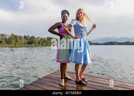 Teenage friends standing on pier over lake, Bavaria, Germany Stock Photo