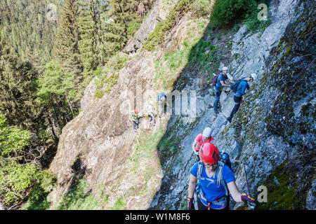 Group of people climbing steep rock face via ferrata towards Stuibenfall Waterfall, Otztal, Tyrol, Austria Stock Photo