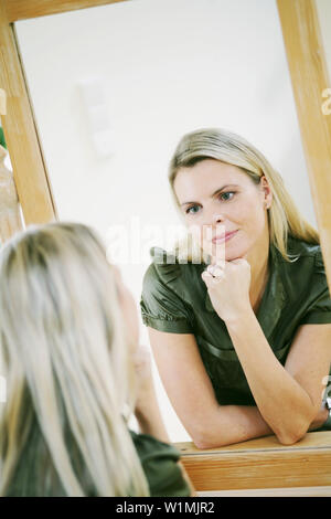 Young woman looking into the mirror, reflected in the mirror Stock Photo
