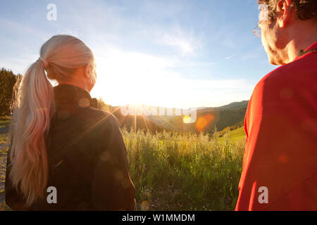 Couple looking at a sunrise above an alpine pasture, Styria, Austria Stock Photo