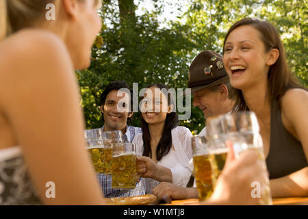 Friends in a beer garden, clinking glasses, Lake Starnberger, Bavaria, Germany Stock Photo