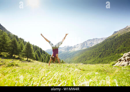Woman doing a cartwheel on a grass field Stock Photo