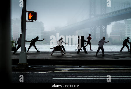Group of people doing Tai Chi in New York's Lower East Side under Brooklyn Bridge Stock Photo