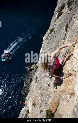 A young woman and a young man climbing on the cliffs at the bay of Zurrieq, Malta, Europe Stock Photo