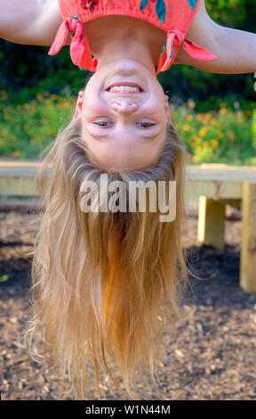 Girl hanging upside down at the park Stock Photo