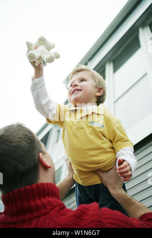 Father lifts son in the air, laughing Stock Photo