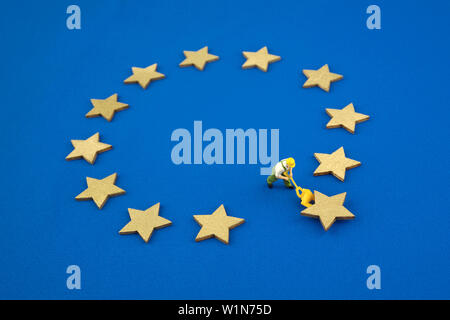 Brexit cocept. The mini figure pushes one star out of the Europen Union Flag. Stock Photo