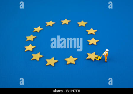 Brexit cocept. The mini figure pushes one star out of the Europen Union Flag. Stock Photo