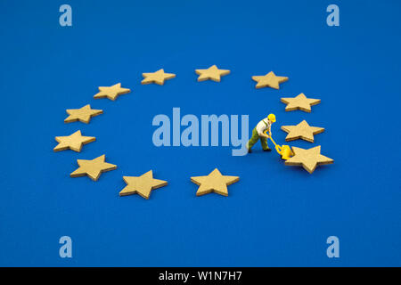 Brexit cocept. The mini figure pushes one star out of the Europen Union Flag. Stock Photo