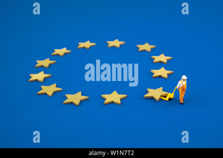 Brexit cocept. The mini figure pushes one star out of the Europen Union Flag. Stock Photo