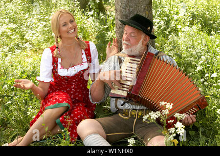 Mature man playing melodeon, woman clapping hands Stock Photo