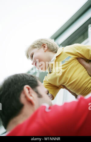 Father lifts son in the air, laughing Stock Photo