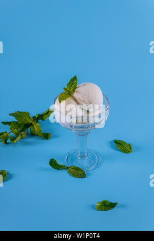 Vanilla ice cream with mint in a glass closeup on blue background. Stock Photo