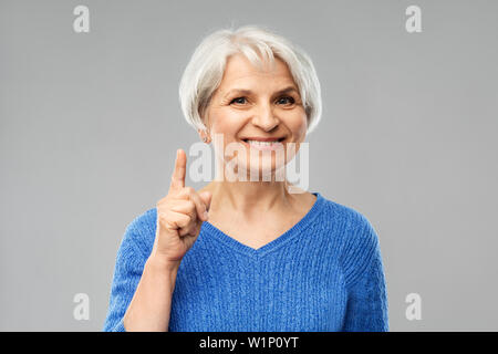 smiling senior woman pointing finger up Stock Photo