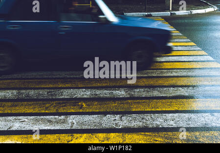 The car passes at high speed on a slippery wet in the rain pedestrian crossing. Stock Photo