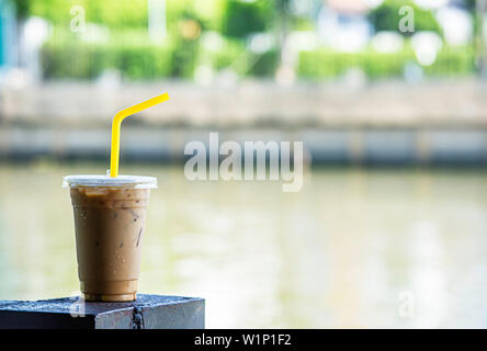 Iced coffee in a glass On the steel rod Blur background river. Stock Photo