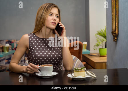 Beautiful serious woman talks on mobile phone in cafe. Portrait picture Stock Photo