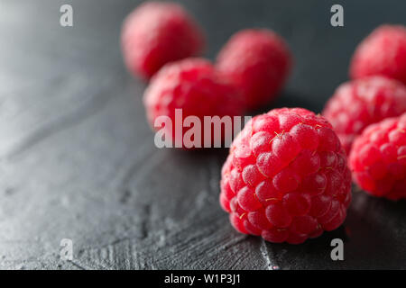 Raspberries on black cement background, closeup and space for text Stock Photo