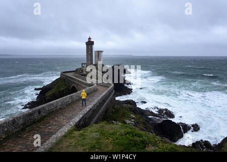 woman in yellow rain jacket walking on the bridge to Phare du Petit Minou, Plouzané, Brest, Finistère département, Bretagne - Brittany, France, Europe Stock Photo